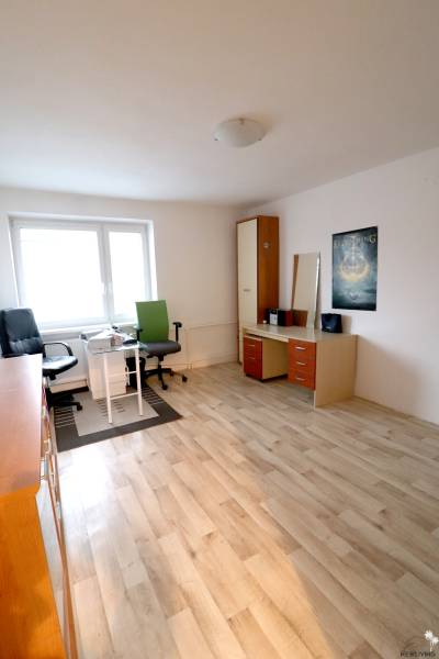 A room with a wooden decor floor, a desk, and a chair in a family house.