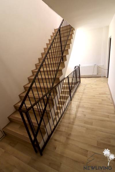 A staircase with a metal railing and a wooden decor floor in a family house.
