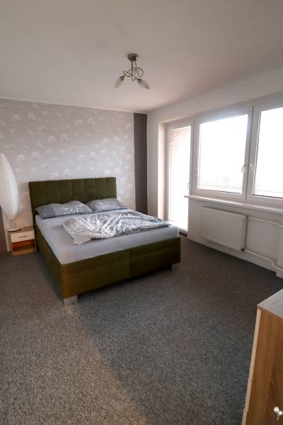 A bedroom in a family house with an upholstered bed and a gray carpet.