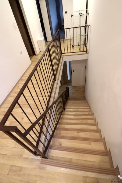 A staircase in a family house with a wooden decor floor and metal railing.