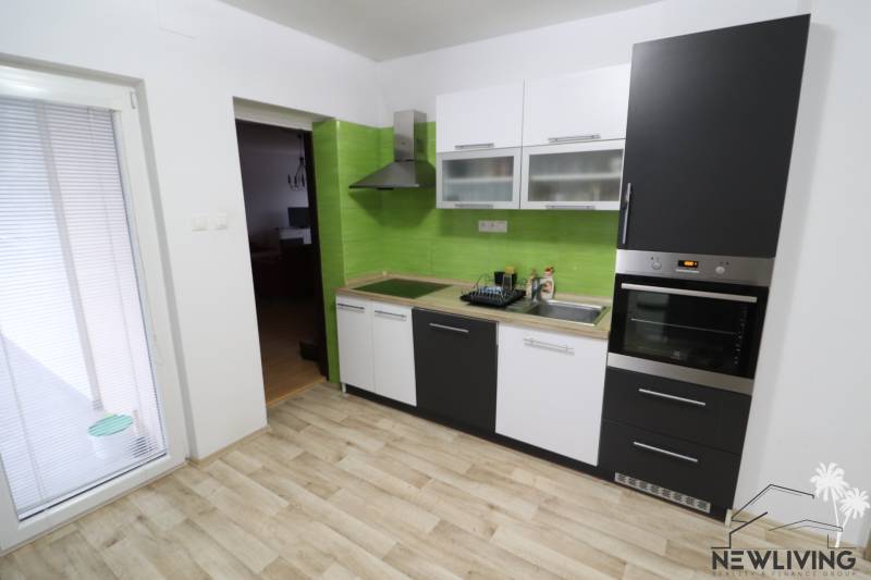 A kitchen in a family house with a wooden decor floor and green tiles.