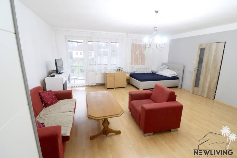 Living room in a family house with a sofa, table, and bed. Floor with wood decor.