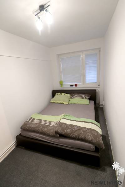 Bedroom with a bed in a family house, white walls, carpet.