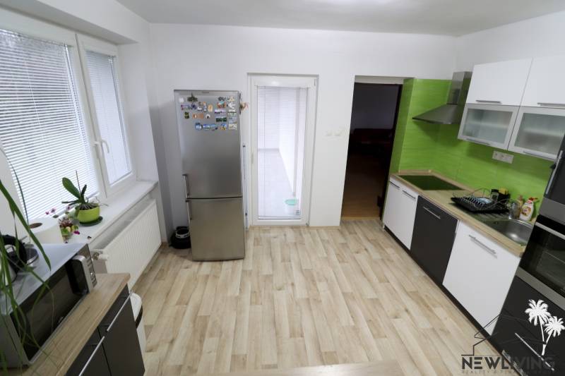 A kitchen in a family house with a wooden decor floor and green tiles.