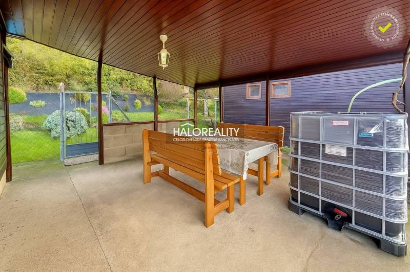 Covered terrace with a table, benches, and a view of the gardens in Bytča.