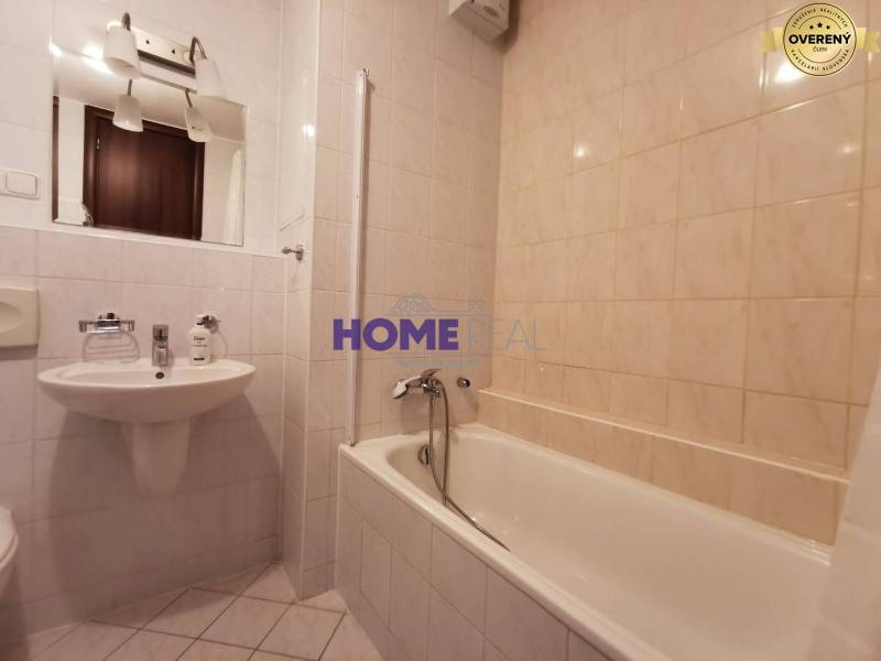 Bathroom in a 2-room apartment with a bathtub, sink, and mirror.