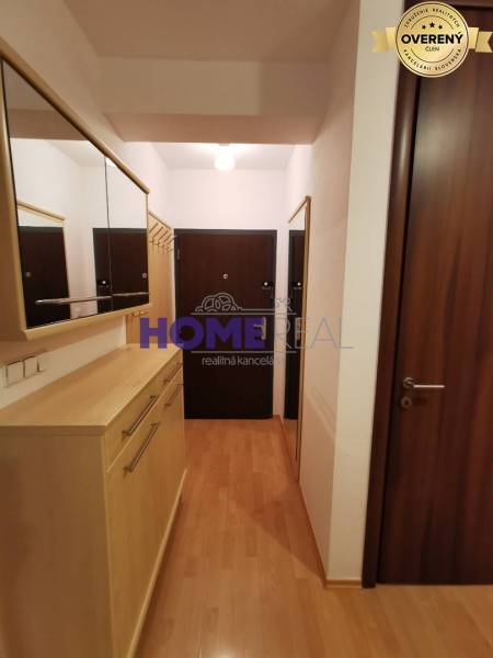 The entrance hall in a 2-room apartment with a wooden decor floor, mirrors, and wardrobes.