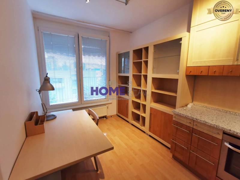 A study in a 2-room apartment with a wooden decor floor, a desk, and a bookshelf.