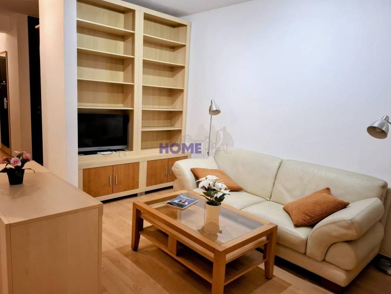 Living room in a two-room apartment with a leather sofa and a built-in shelf.