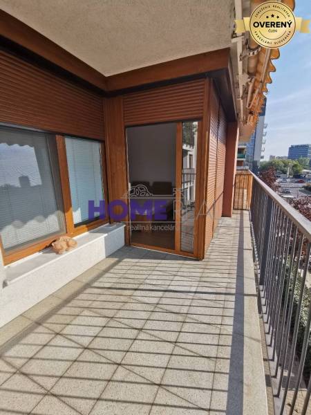 A balcony with tiles, wooden windows, and a view of the surroundings in a 2-room apartment.