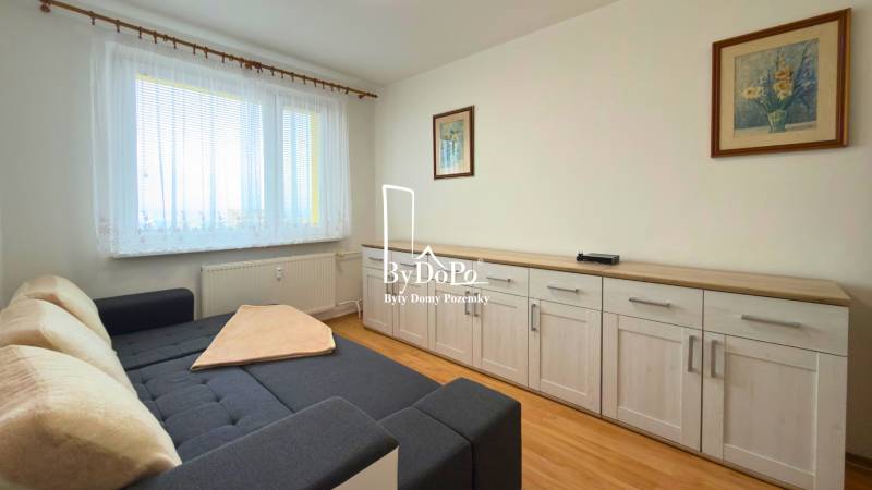 A room with a sofa, furniture, and a floor with wooden decor in a 3-room apartment.