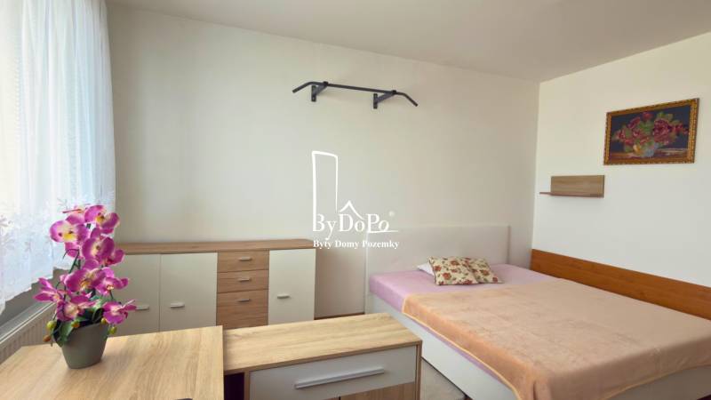 A bedroom with a bed, wardrobe, and decorative flowers in a 3-room apartment.