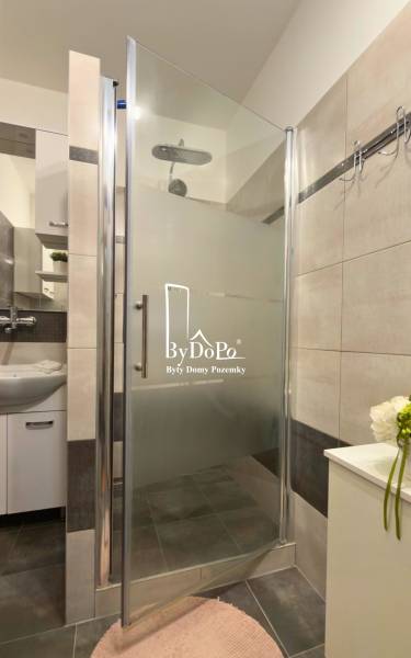 A shower corner with modern tiles and a sink in a 3-room apartment.