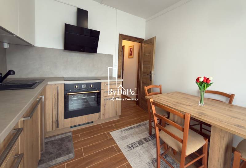 A kitchen in a 3-room apartment with a wooden decor, a dining table, and a kitchen unit.