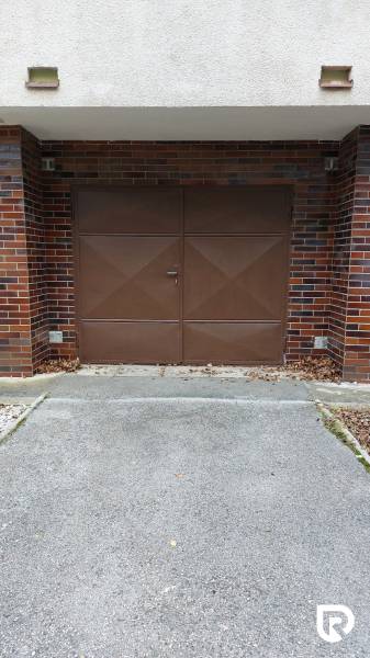 Garage in front of the field in Trenčín with brown doors and brick cladding, 3-room apartment.