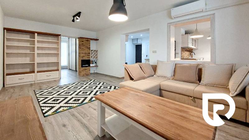 A living room in a three-room apartment with a wooden decor floor and comfortable seating.