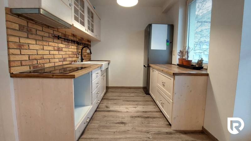 A kitchen in a 3-room apartment with a wooden decor floor and brick cladding.