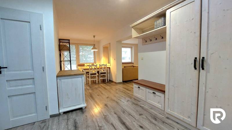 Interior of a 3-room apartment with a wooden decor floor and a dining table.