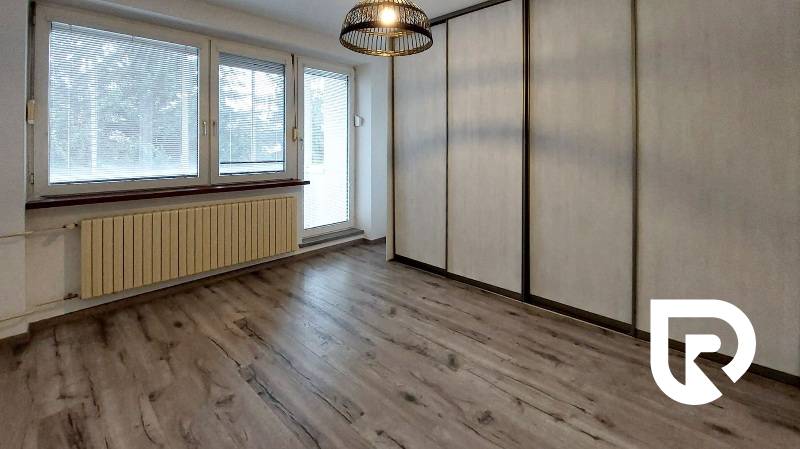 A room with a wooden decor floor and built-in wardrobes in a 3-room apartment.