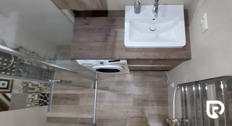 Bathroom in a 3-room apartment with a washing machine and a wooden decor floor.