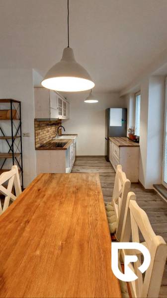 A kitchen in a 3-room apartment with a rustic table and bright lighting, flooring with a wooden decor.