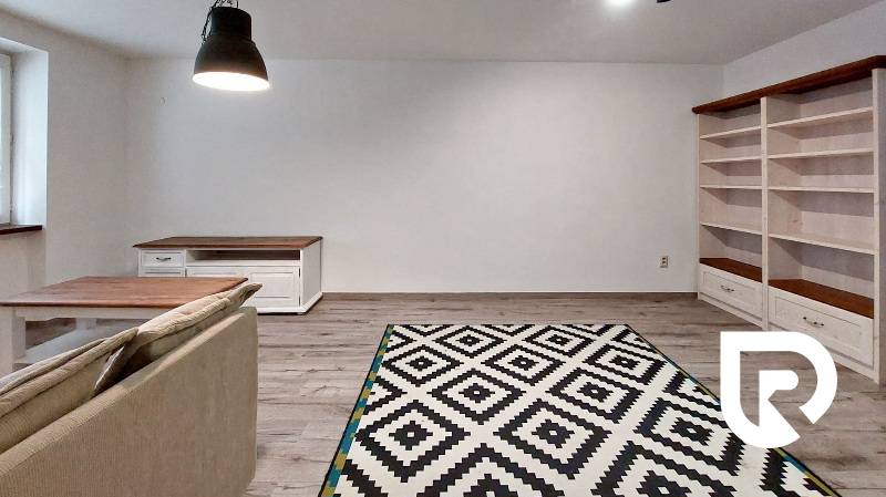Living room in a three-room apartment with a wooden-patterned floor and a patterned carpet.