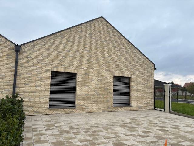 A family house on Fialkova Street in Tomášov with a brick facade and a paved courtyard.