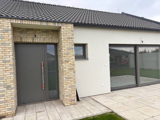 Family house on Fialkova in Tomášov with brick cladding and spacious glass doors.