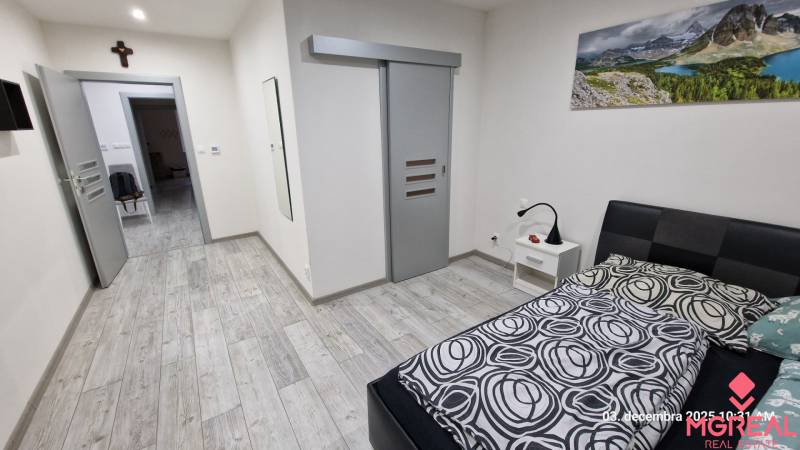 A bedroom in a family house with a wood-patterned floor and sliding doors.