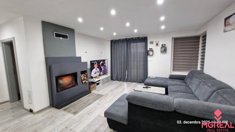 Living room in a family house with a fireplace, gray sofa, and television, wooden decor flooring.