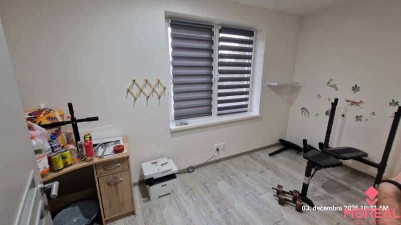 A room in a family house with a wooden decor floor, a weight bench, and a table.