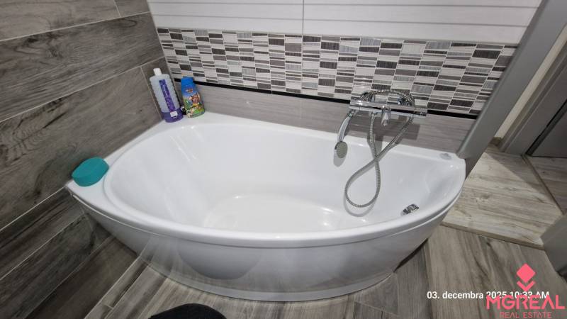 In the bathroom of the family house, there is a white bathtub with tiles and a faucet.