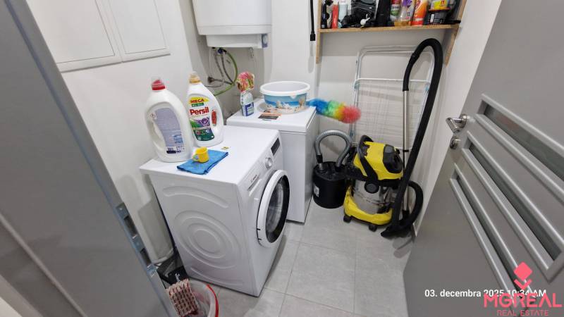 Laundry room in a family house with a washing machine, dryer, cleaning products, and a vacuum cleaner.
