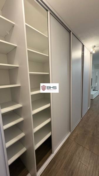 Built-in wardrobe in a studio apartment with sliding doors and a wooden decor floor.