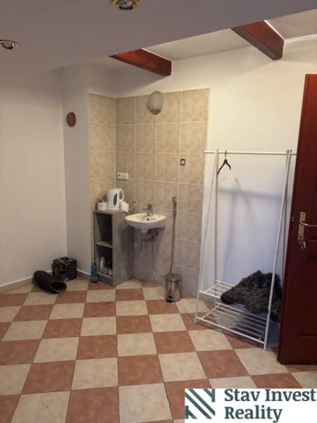 Interior of an office with a sink, coat rack, and tiled floor.