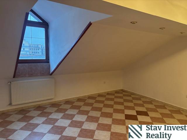 Attic office with tiles and a window, heated by a radiator.