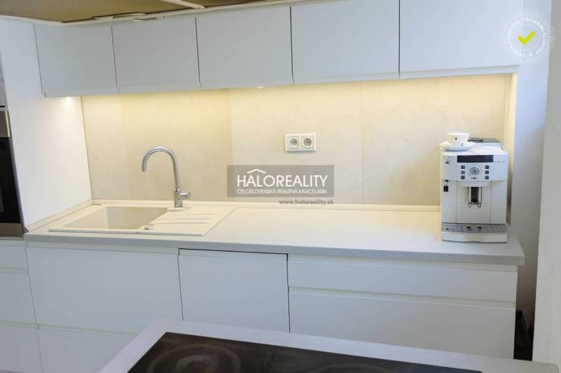 A kitchen with white cabinets and a coffee maker in a 3-room apartment.