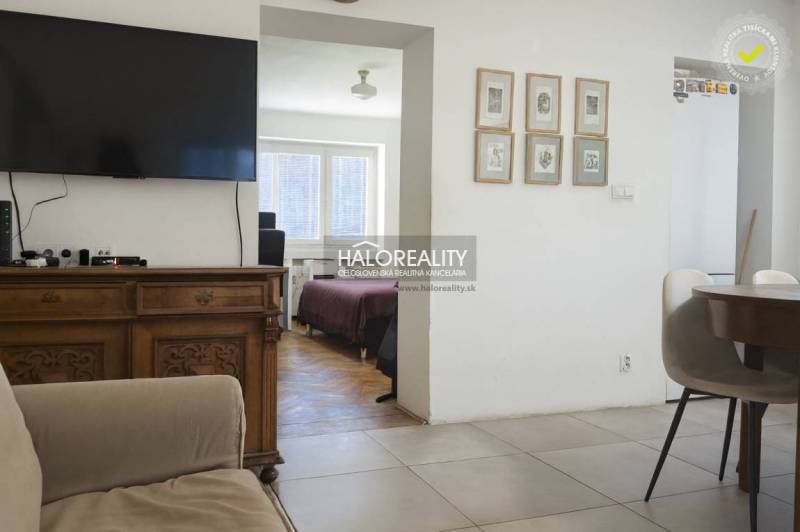 Living room with a television, chairs, and a view of the bedroom in a three-room apartment.