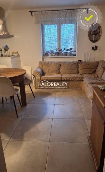Living room of a 3-room apartment with a sofa, dining table, and tiled floor.