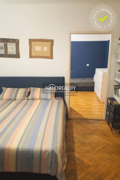 Bedroom in a 3-room apartment with a wooden decor floor and colorful bed linen.
