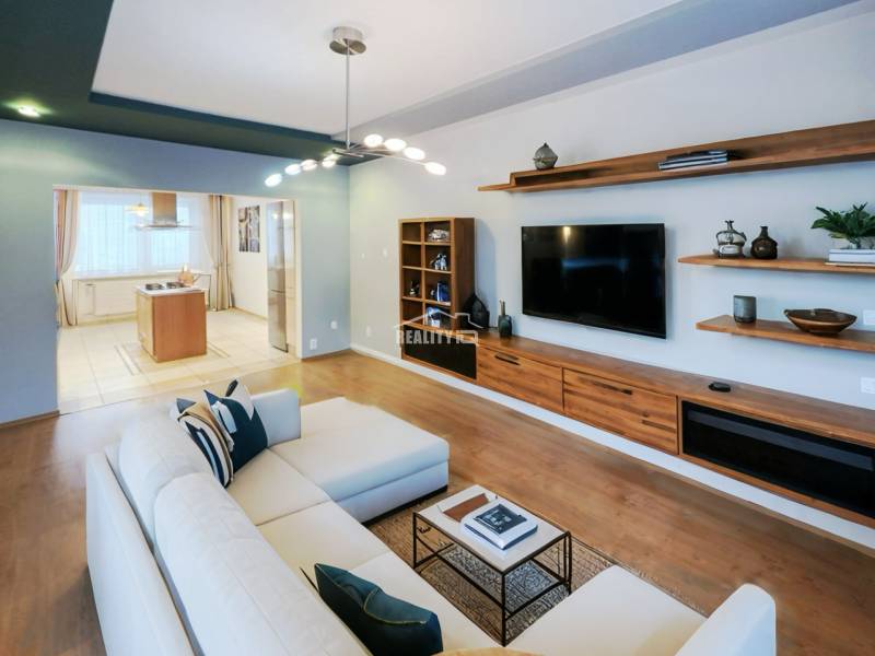 Living room in a 4-room apartment with a wooden decor floor, television, and sofa.