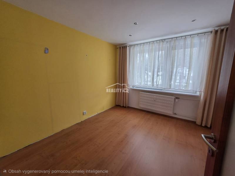A room with a yellow wall, a window with delicate curtains, and a floor with a wooden decor.