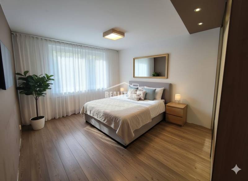 Bedroom with a bed, mirror, and nightstands in a 4-room apartment with a wood-patterned floor.