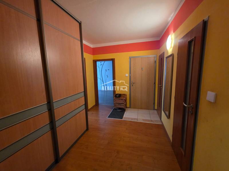A hallway in a 4-room apartment with a wooden decor floor and built-in wardrobes.