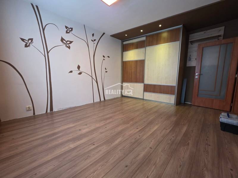 A room in a 4-room apartment with a wooden decor floor and decorative wall elements.