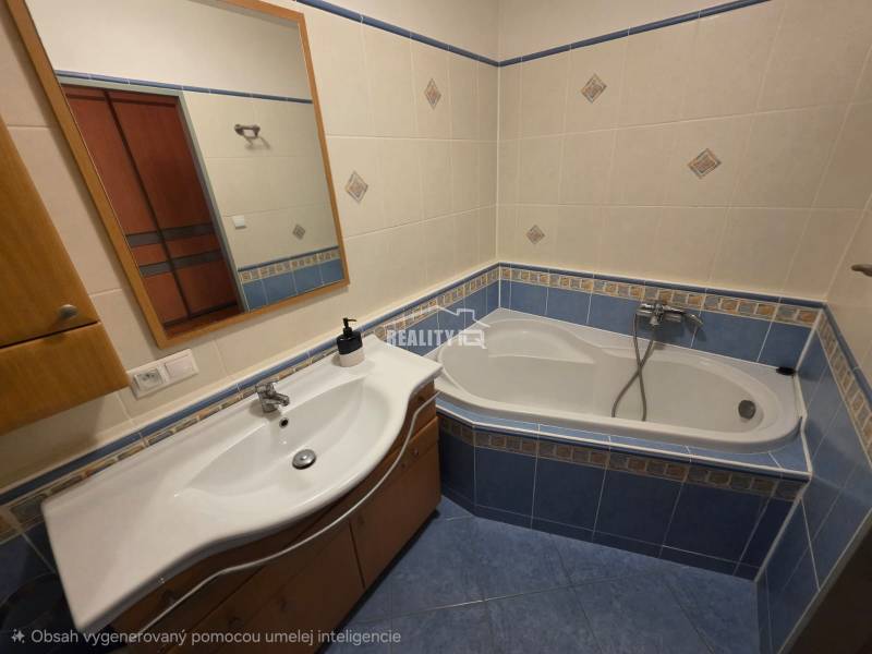 A bathroom in a 4-room apartment with a sink, mirror, and bathtub with blue tiles.