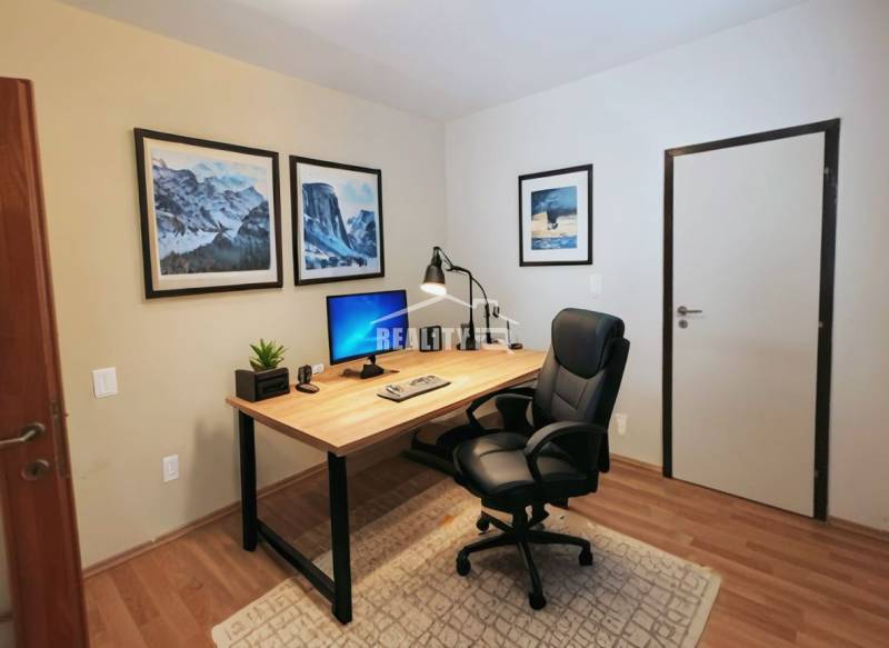 Office corner in a 4-room apartment with a desk and wooden decor flooring.