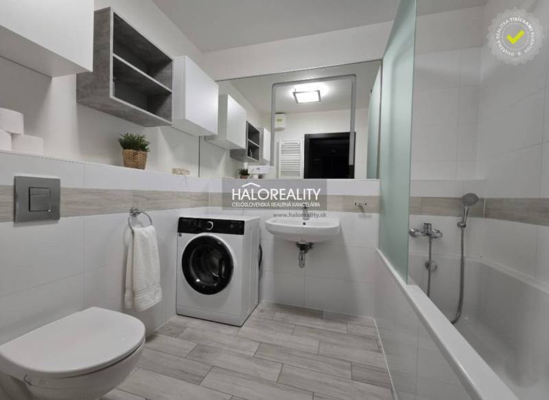 A bathroom in a 2-room apartment with a shower, a washing machine, and a floor with a wooden decor.