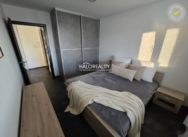 Bedroom in a 2-room apartment with dark flooring, a large wardrobe, and simple furniture.