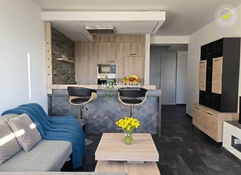 Living room in a two-room apartment with an open kitchen and a wooden decor floor.